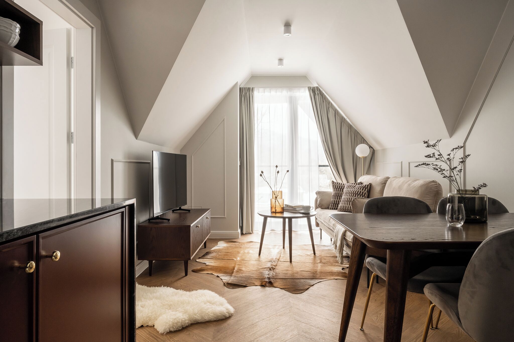 A modern loft apartment with a dining area, a sofa, and a television.