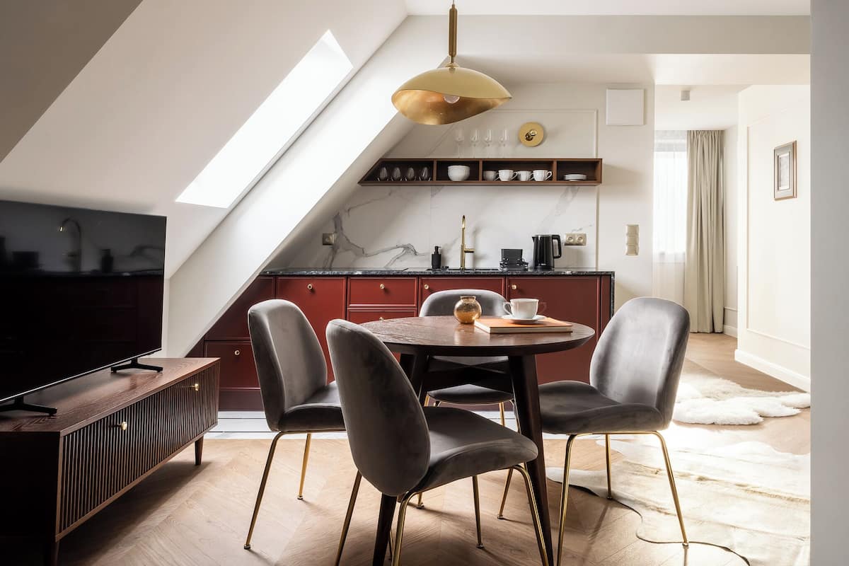 A modern kitchen with a skylight, dark wood cabinetry, and a dining area with a round table and chairs.