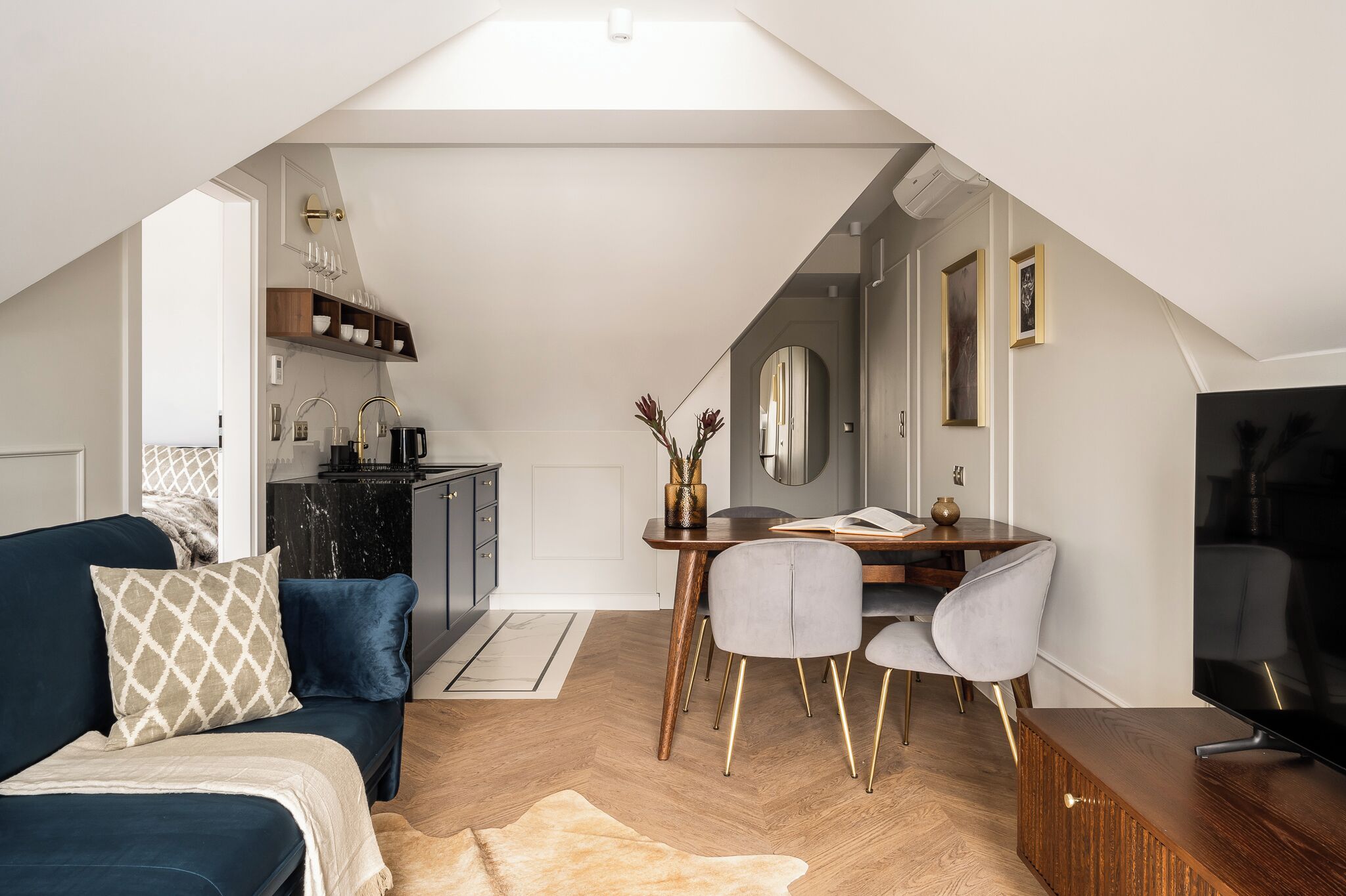 A modern loft apartment with a dining area, a sofa, and a TV.