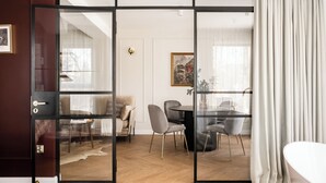 A modern living room with a glass door leading to a dining area, a sofa, and a painting on the wall. - Renesans Residence Zakopane (Zakopane)