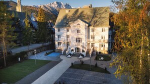 A large, multi-story building with a symmetrical facade, a central entrance with a staircase, and a surrounding courtyard with a swimming pool. - Renesans Residence Zakopane (Zakopane)
