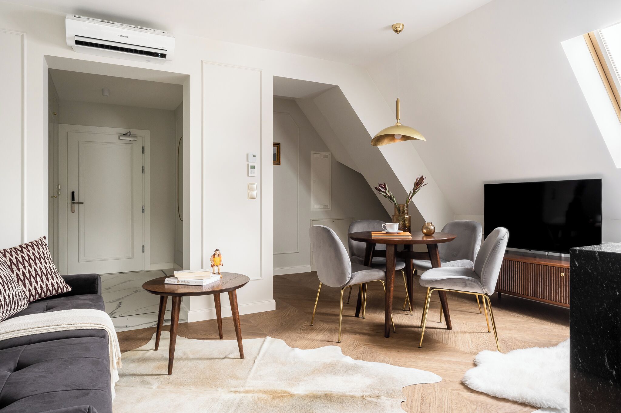Un salon moderne comprenant un canapé, une table à manger avec des chaises, un téléviseur et un ventilateur de plafond.