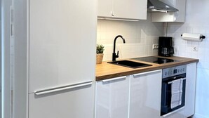 Een moderne keuken met witte kasten, een houten aanrechtblad, een zwarte kraan en een inbouwoven.