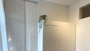 Een kamer met een houten vloer, een witte kast en een hangplant.