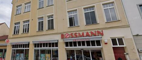 Un edificio con el rótulo 'ROSSMANN', con varias ventanas y un escaparate que muestra productos.