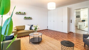A modern living room with a sofa, a coffee table, and a dining area with a kitchen in the background. - Spacious Apartment In Strausberg - Sleeps 6 (Strausberg)