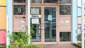 Ein Gebäude mit Glastür, einem Schild mit der Aufschrift 'Eingang' und der Nummer 9 an der Tür.