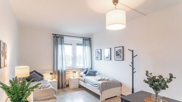 Ein modernes Schlafzimmer mit einem Bett, Nachttischen, einem Schreibtisch und einem Topfpflanzen.