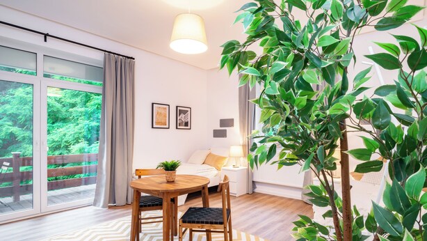 Ein modernes Zimmer mit Essbereich, einem Bett und einem großen Fenster mit Blick auf eine Terrasse.