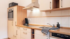 Eine moderne Küche mit weißen Schränken, einer Holzarbeitsplatte, einem eingebauten Backofen, einer Kaffeemaschine und einem Geschirrspüler.