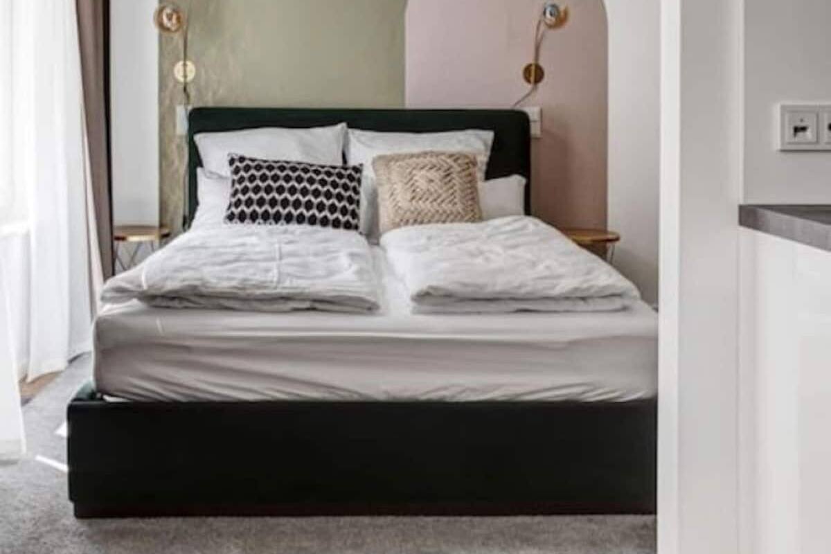 Un dormitorio moderno con cama, ventilador de techo y un amplio arco en la pared.