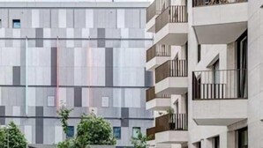 A modern building with a geometric facade, outdoor seating, and a landscaped area with trees. - Arbio I Luxury Apartments (Berlin)