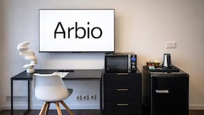 Un espace de bureau moderne comprenant un bureau, une chaise, un téléviseur à écran plat, un four à micro-ondes et une machine à café.