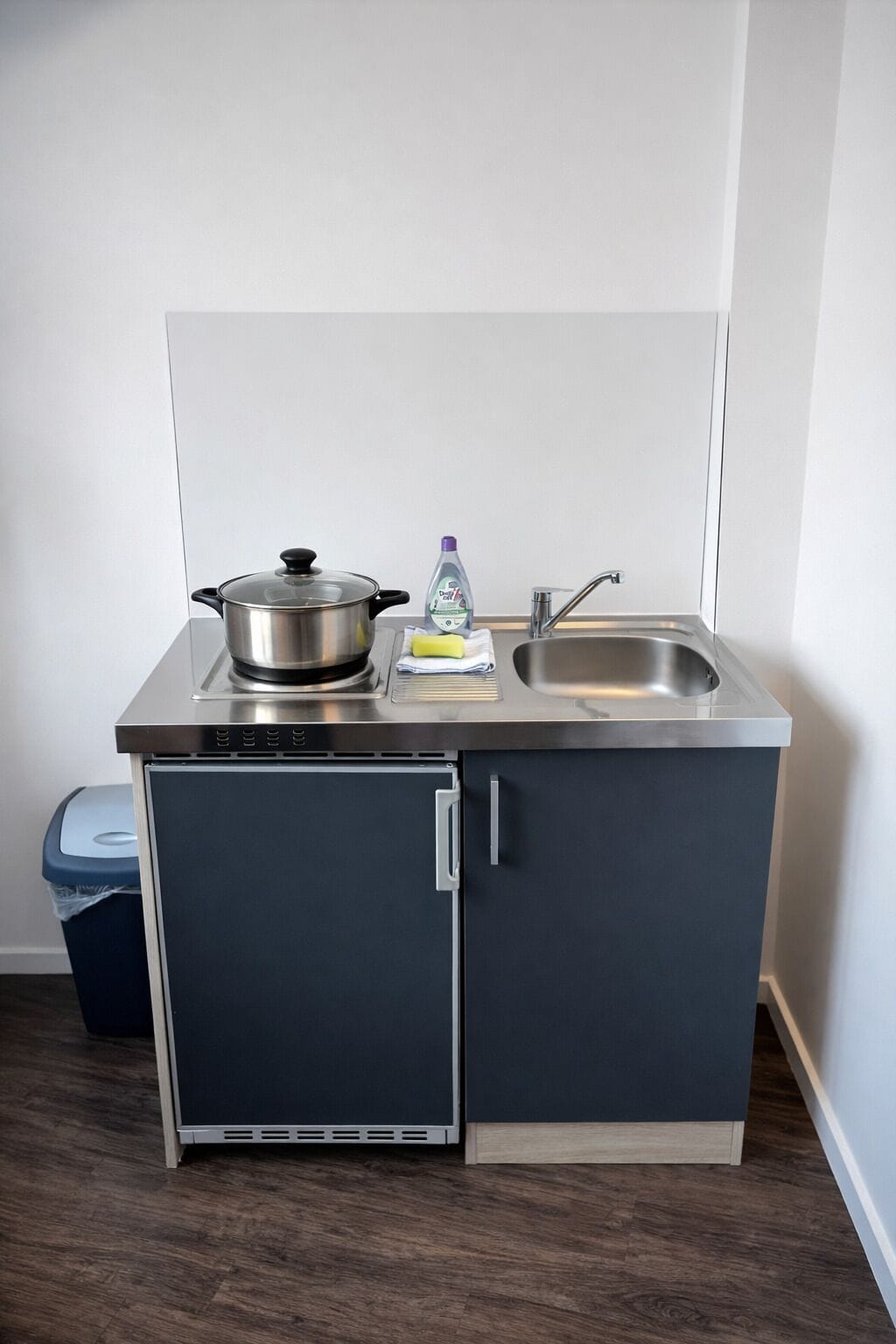 A compact kitchenette with a stove, sink, and storage cabinet.