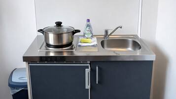 A compact kitchenette with a stove, sink, and storage cabinet.