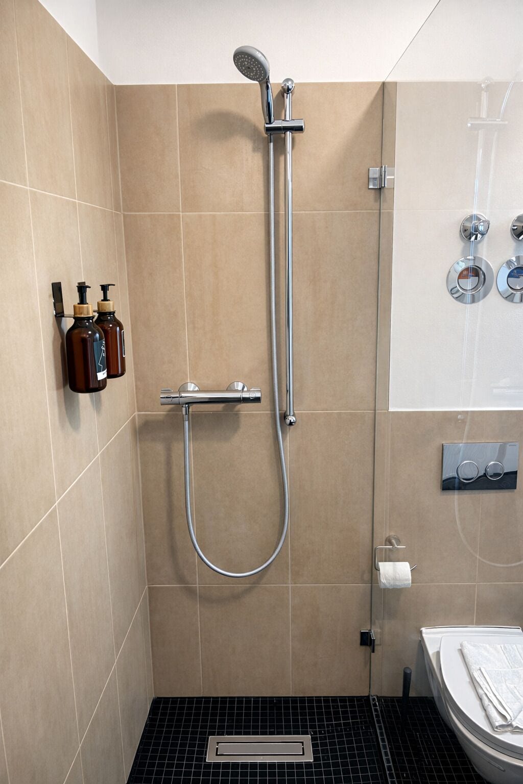 Et moderne badeværelse med bruser, toilet og håndvask.