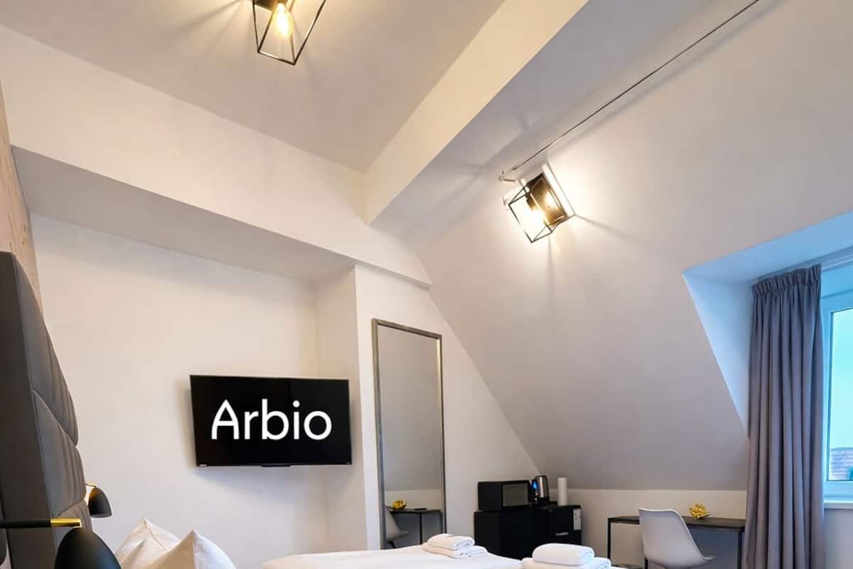 A modern hotel room with a bed, a flat-screen TV, a desk, and a large window.