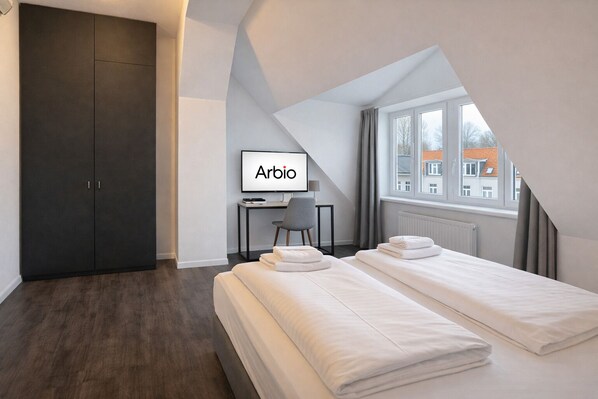 Ein modernes Hotelzimmer mit zwei Betten, einem Schreibtisch, einem Stuhl und einem großen Fenster.