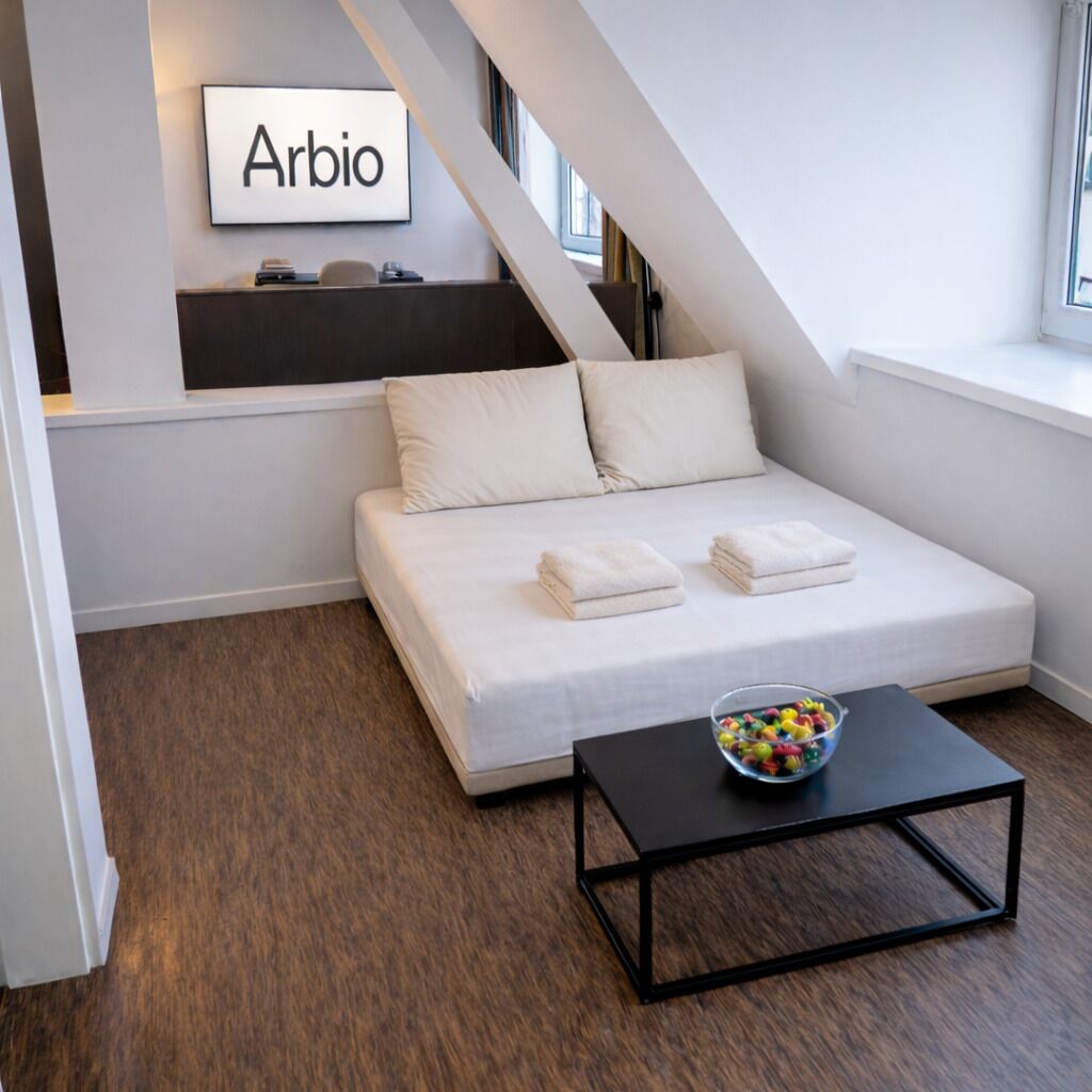 Un dormitorio moderno con una cama alta, un escritorio pequeño y una ventana.
