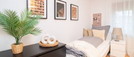 Un dormitorio moderno con cama, mesita de noche, lámpara y decoración en la pared.