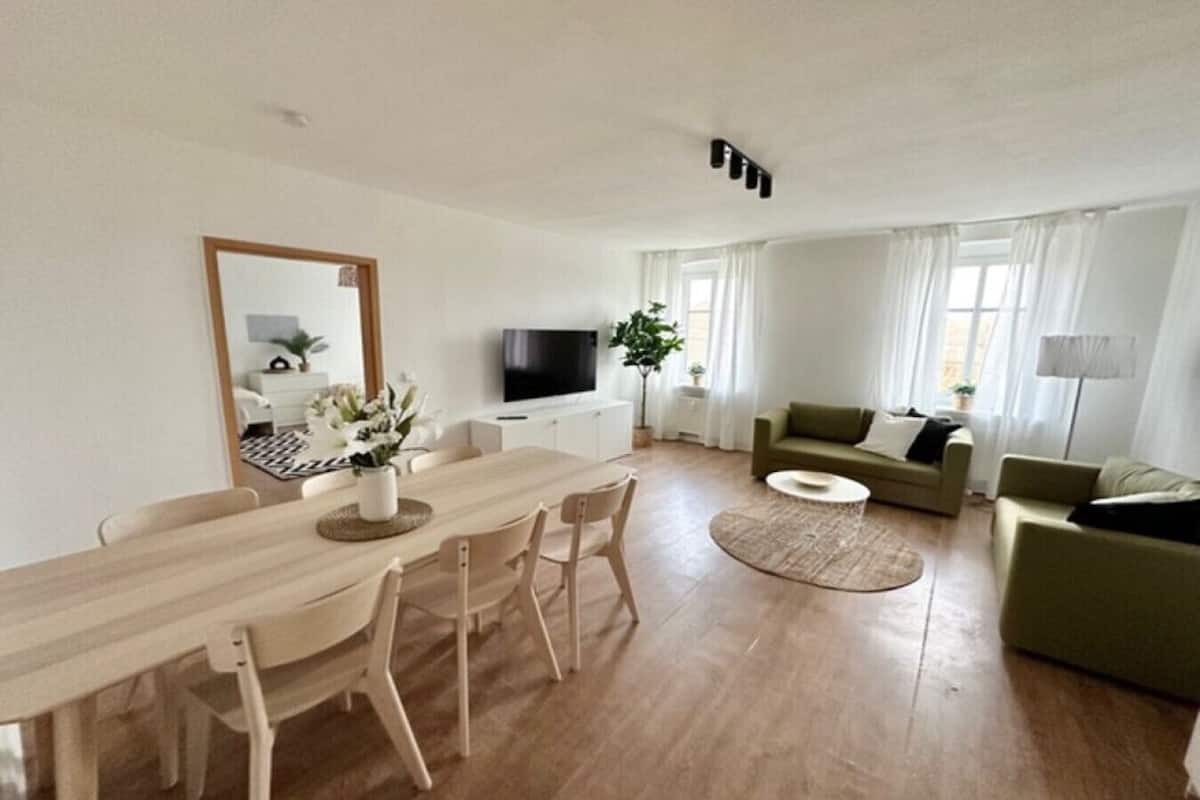Un salon moderne avec une table à manger en bois, un canapé et un téléviseur.