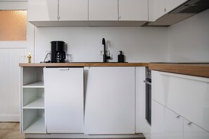 Una cocina con armarios blancos, encimera de madera, cafetera y lavavajillas.