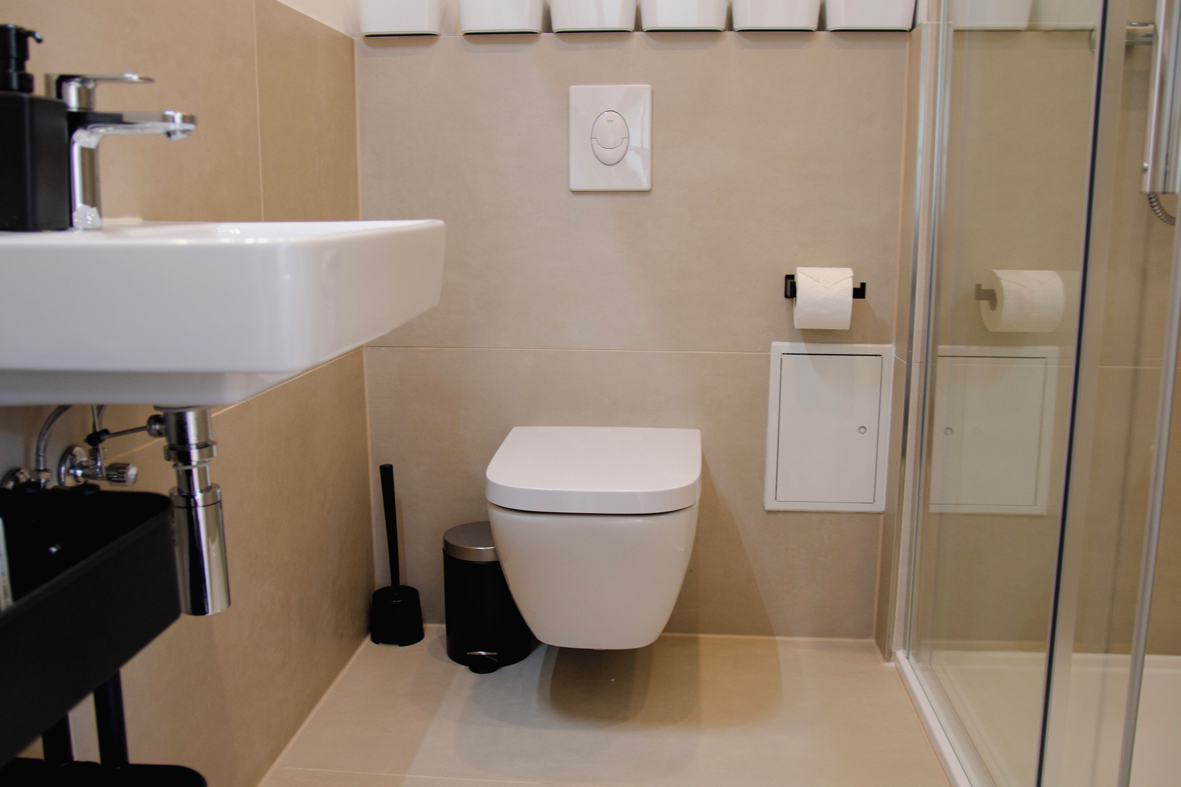 A modern bathroom with a white sink, toilet, and shower.