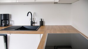 Uma cozinha com pia preta, cafeteira e fogão por indução embutido.
