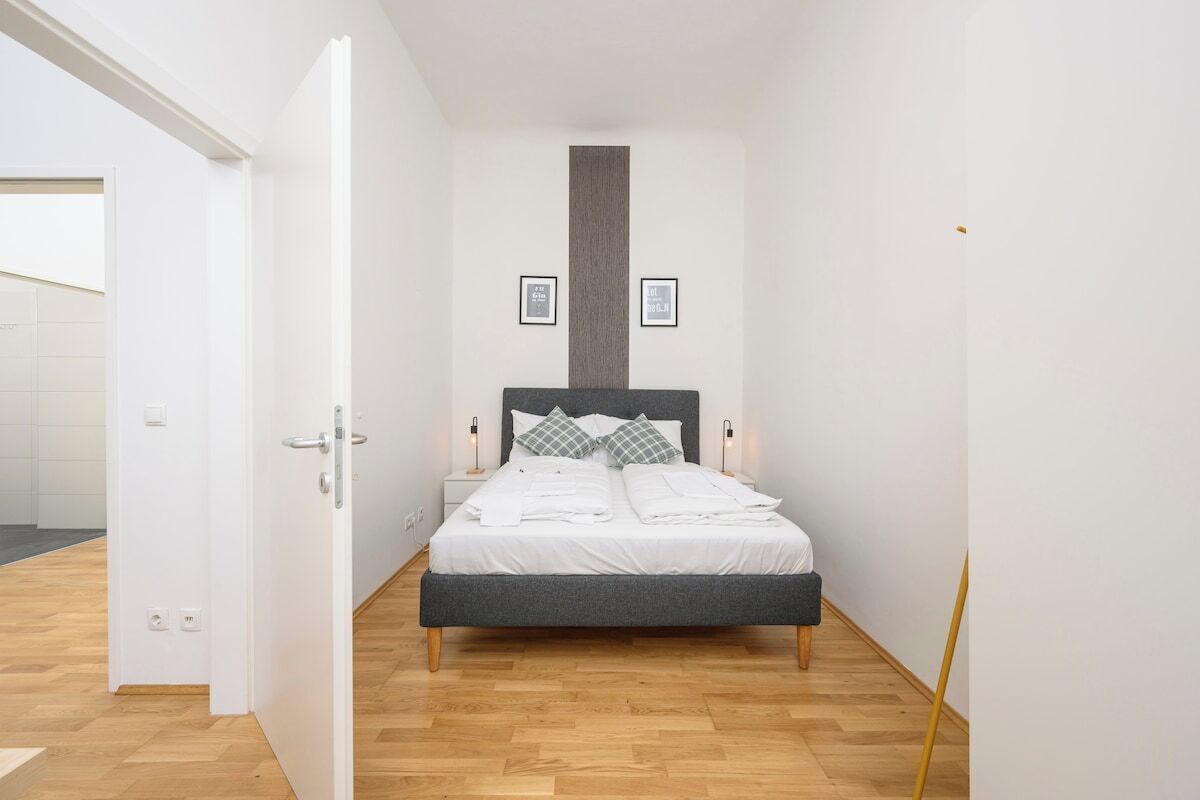 A bedroom with a bed, bedside tables, and a door.