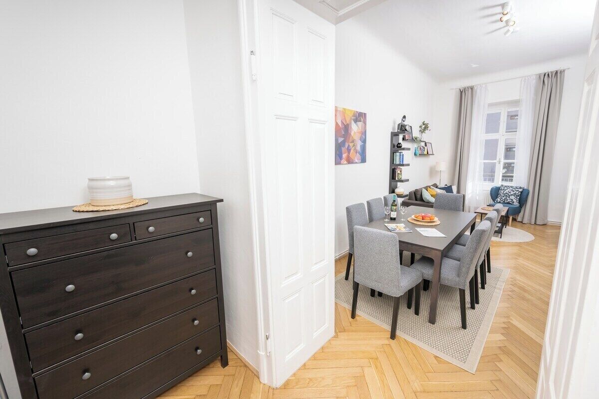 A modern dining area with a dark wooden dresser, a dining table with chairs, and a window with curtains.