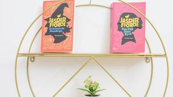Una estantería dorada con dos libros titulados 'JASPER FÖRDE' y una pequeña planta en maceta.