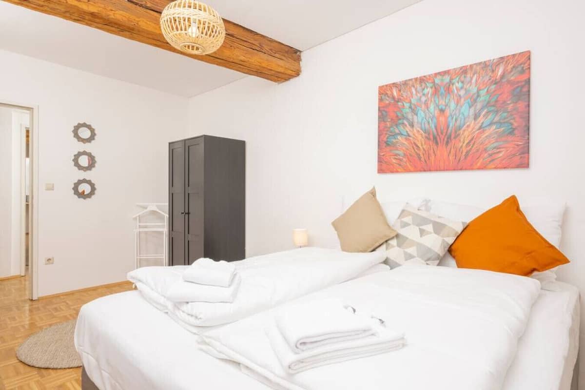 Ein Schlafzimmer mit Bett, Kleiderschrank, Wandbild und Pendelleuchte.
