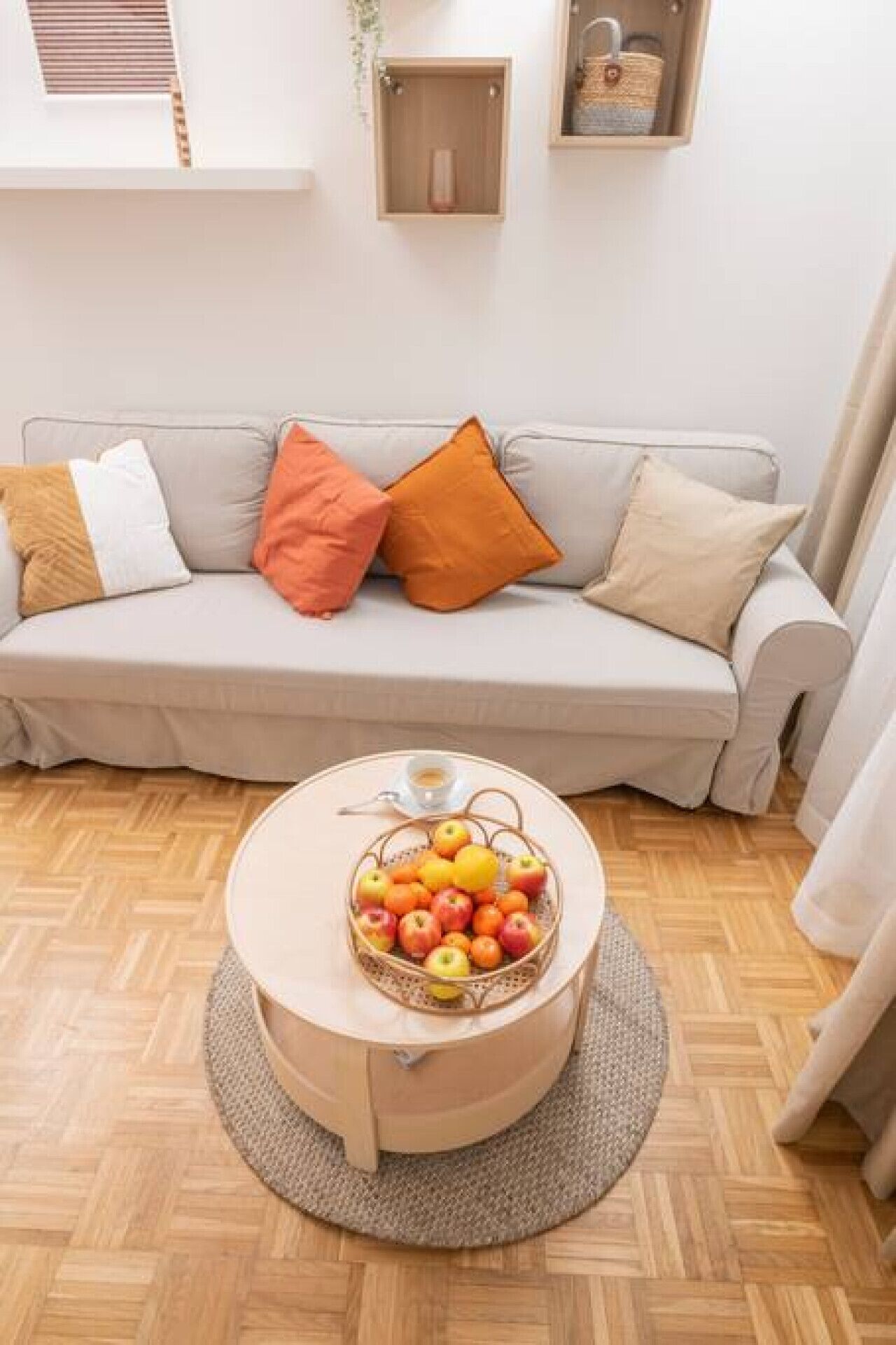 Ein Wohnzimmer mit einer Couch, einem runden Couchtisch mit Obstschale und einer Holzkabine.