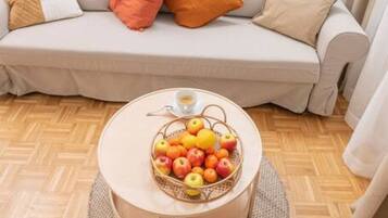 Ein Wohnzimmer mit einer Couch, einem runden Couchtisch mit Obstschale und einer Holzkabine.
