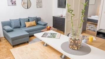 A modern living room with a grey sofa, a white coffee table, and a decorative plant centerpiece.
