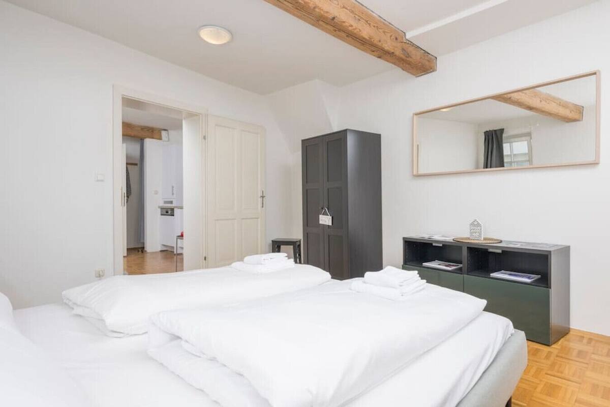 Ein Hotelzimmer mit zwei Betten, einem Kleiderschrank, einem Spiegel und einem kleinen Tisch mit einem Korb.