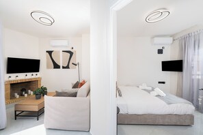 Une chambre d’hôtel moderne dotée d’une cheminée, d’un téléviseur à écran plat, d’un lit et d’une grande fenêtre.
