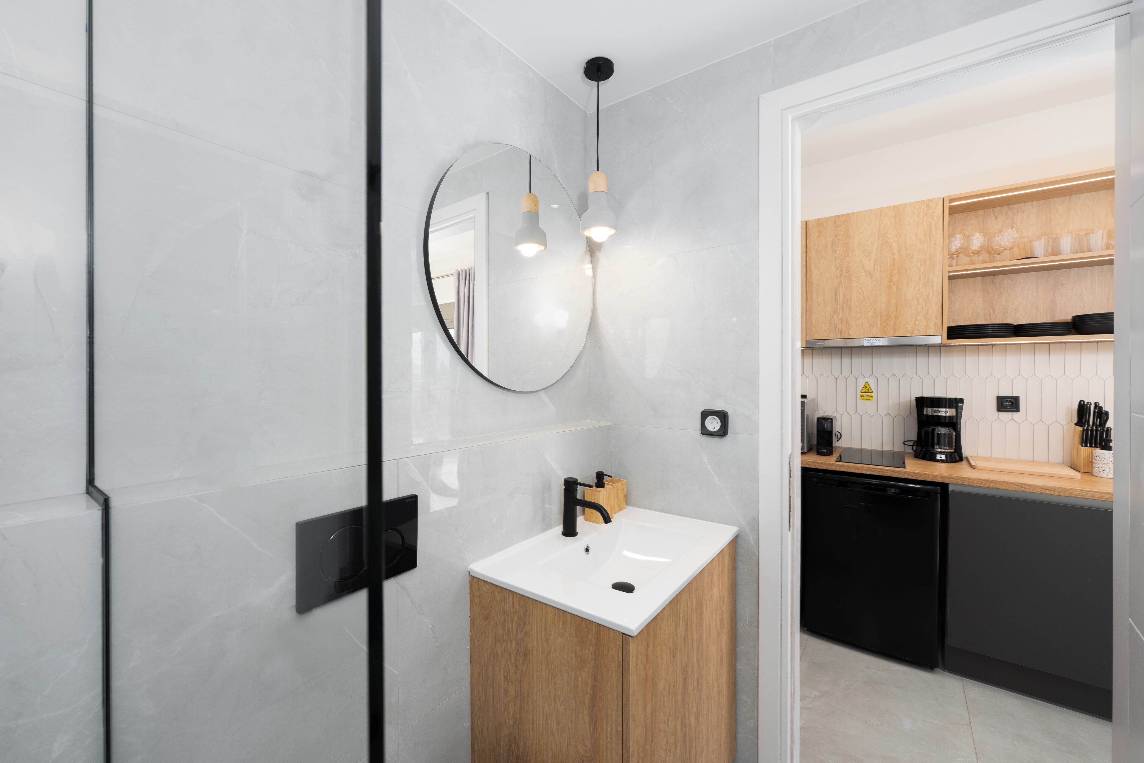 Une cuisine moderne avec un évier blanc, des meubles en bois et un lave-vaisselle noir.