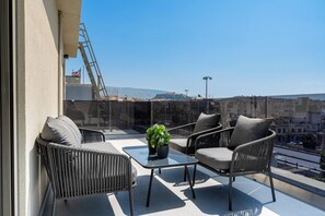 Un balcon agrémenté de meubles en osier, d’une table en verre et d’une plante en pot.