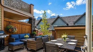 An outdoor patio with a grill, seating, and a dining table set for four.