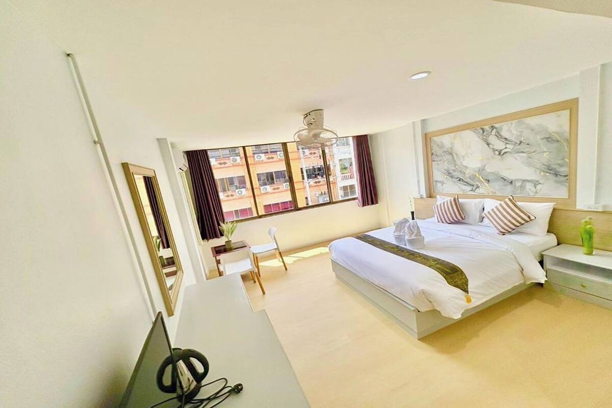 Habitación de hotel moderna con una cama grande, un escritorio y vistas a un edificio desde la ventana.