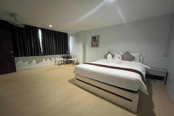 A bedroom with a large bed, a desk, and a chair.