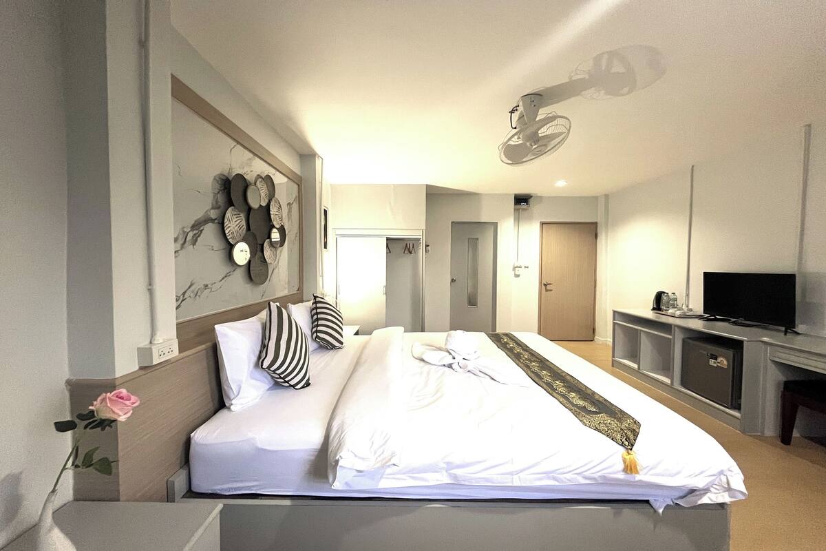 Una habitación de hotel moderna con una cama grande, televisión y espejo.