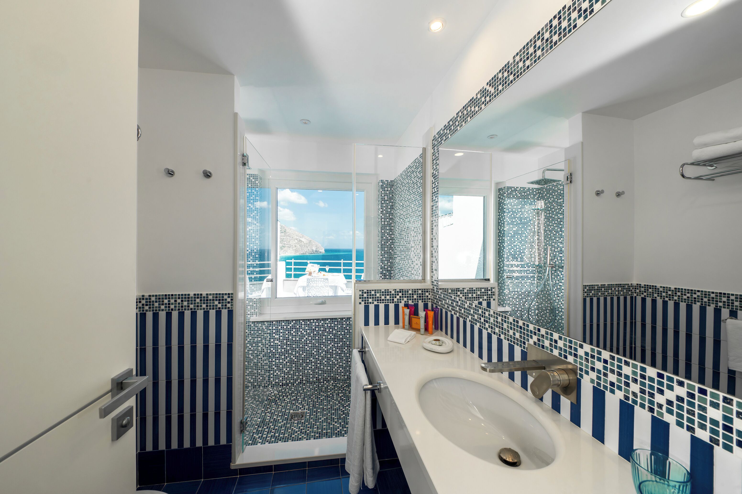 A modern bathroom with a large mirror, a sink, and a shower.