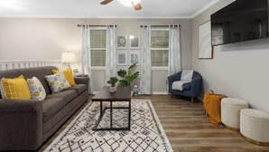 Un salon avec un canapé, une table basse et un téléviseur fixé au mur.