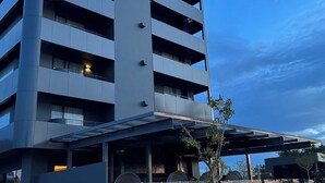 Un edificio moderno con un letrero que dice "LE PÔTIF" y un espacio al aire libre cubierto con luces esféricas.