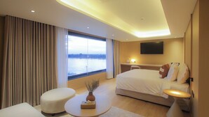 Habitación de hotel moderna con una cama grande, un escritorio, un televisor y vistas a un cuerpo de agua.