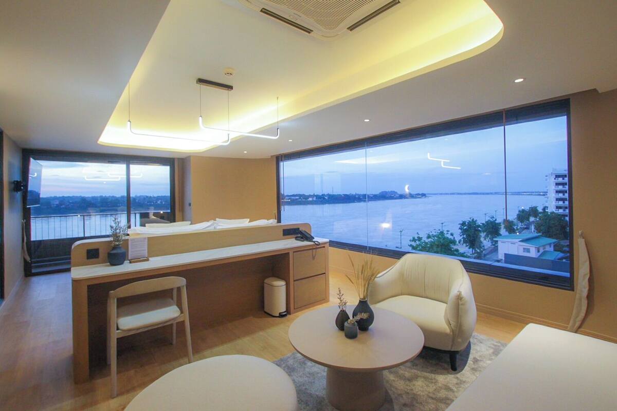 Ein modernes Hotelzimmer mit großem Fenster und Blick auf Wasser und Stadtlandschaft.