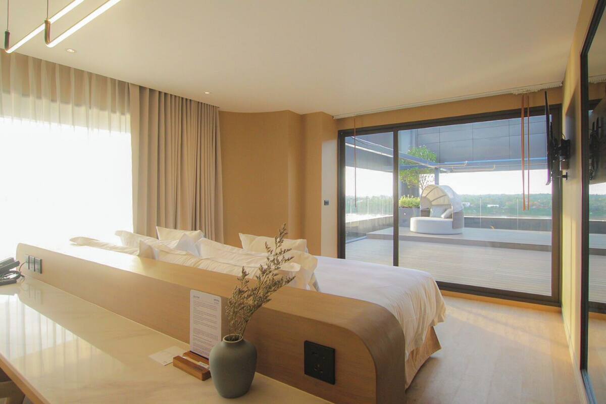 Ein modernes Hotelzimmer mit einem großen Bett, einem Schreibtisch und Blick auf eine Dachterrasse.