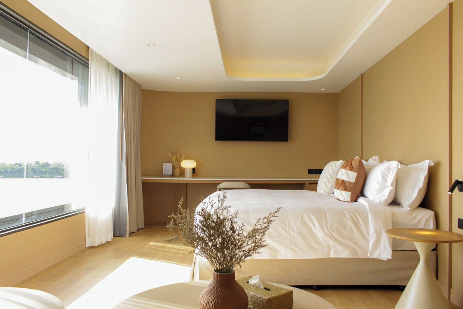 Een hotelkamer met een bed, nachtkastje, televisie en uitzicht op het omliggende landschap.